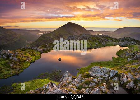 Fantastico tramonto serale sulla catena montuosa del Lake District con riflessi in acqua. Viste pittoresche dal famoso paesaggio britannico; Haystack. Foto Stock
