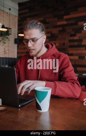 Ritratto di happy maschio freelancer in ottica eyewear per la correzione della visione sorridendo alla fotocamera durante la pausa dal web di lavoro online, allegro hipster bl Foto Stock