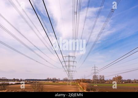 Riprese con droni di poli di potenza appena sotto le linee elettriche nelle zone rurali della Germania Foto Stock