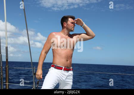 Giovane uomo che naviga la sua barca sull'oceano aperto Foto Stock