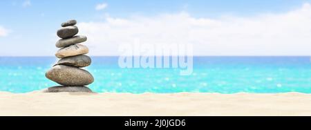 Pietre equilibrato su una spiaggia di ciottoli durante il tramonto. Foto Stock