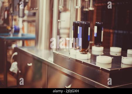 Bottiglie di vino pronte per essere riempite con vino da una macchina industriale in una cantina Foto Stock