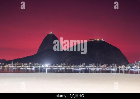 Cielo con il colore rosso, sotto l'influenza delle ceneri del vulcano di tonga nella baia di Botafogo a Rio de Janeiro, Brasile. Foto Stock