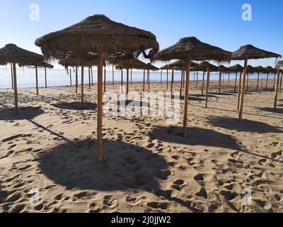 Ombrelloni in spiaggia in inverno. Fuengirola, provincia di Malaga, Spagna. Foto Stock