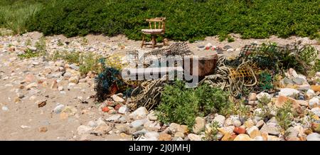 Vecchie trappole di aragosta e corda in un mucchio di rifiuti su una spiaggia circondata da rocce a Narragansett Rhode Island. Foto Stock