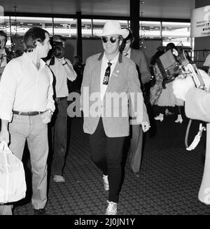 Vestito con un cappello stetson, Elton John lascia l'aeroporto di Heathrow per l'America. 10th agosto 1980. Foto Stock