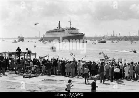 Il QE2 torna a casa a Southampton. Union Jacks è festooned sulle automobili, drappeggiato sulle spalle, ondulato sui bastoni. Southampton dà il benvenuto a "Three Cheers" al QE2 lussuoso liner trasformato in trooper di ritorno dalla guerra. A bordo è il suo prezioso carico, i 700 sopravvissuti della HMS Coventry, ardent e Antelope, affondati nella battaglia per le Falklands. 11th giugno 1982. Foto Stock