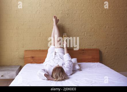 Donna in accappatoio bianco con un bicchiere di champagne nelle mani Foto Stock