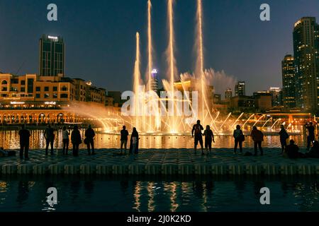 Sagome di persone godendo la fontana show di Dubai di notte, Emirati Arabi Uniti Foto Stock