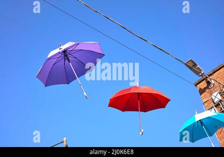 Appendere un ombrello colorato in centro città Foto Stock