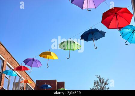 Appendere un ombrello colorato in centro città Foto Stock