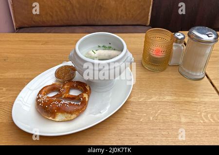 Specialità bavaresi: Weisswurste portato al tavolo in una grande ciotola nell'acqua di cottura. Foto Stock