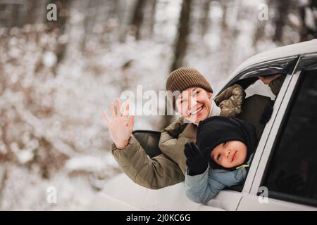 Madre e figlio felici che agitavano le mani dal finestrino dell'auto Foto Stock