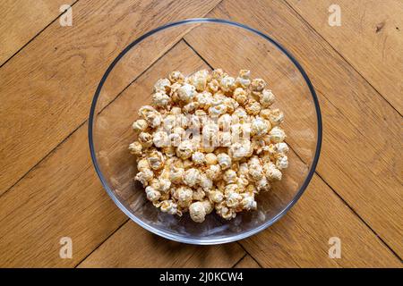 Vista dall'alto del popcorn in una ciotola di vetro trasparente su un tavolo di legno Foto Stock