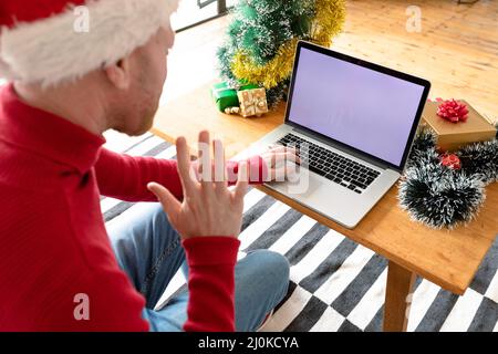 Albino african american uomo che indossa santa Hat fare videochiamata su un portatile con spazio copia Foto Stock