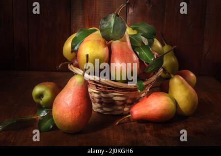 Pere in un cestino su sfondo di legno scuro in stile rustico Foto Stock