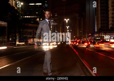 Avete visto una città fino a quando non lo avete visto a piedi. Un uomo d'affari trasparente che attraversa una strada trafficata di notte. Foto Stock