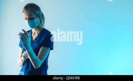 Infermiera focalizzata che si prepara per l'intervento chirurgico. Assistente caucasico che mette su un guanto bianco del lattice per impedire che i batteri spargano fuori. Foto di alta qualità Foto Stock