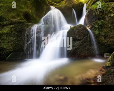 Cascata a lunga esposizione su rocce marroni e verdi a Bad Kreuzen Austria Foto Stock