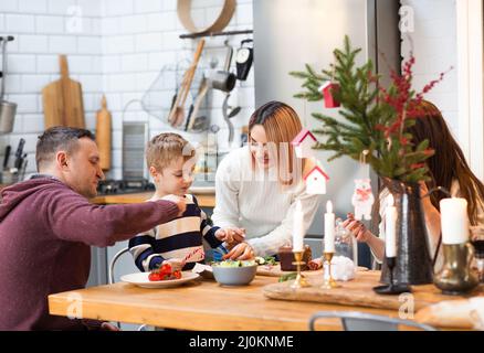 Genitori con bambini in cucina durante le vacanze di Natale Foto Stock