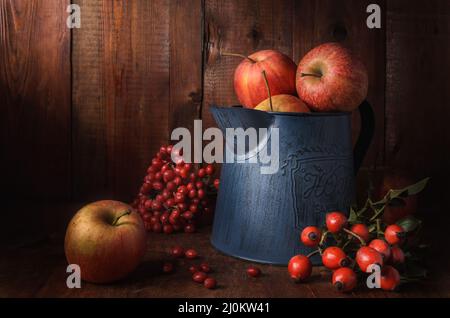 Mele in una brocca da giardino su sfondo di legno scuro in stile rustico Foto Stock