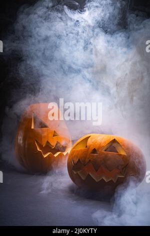 Composizione di zucche intagliate di Halloween e nube di fumo con spazio copia su sfondo nero Foto Stock