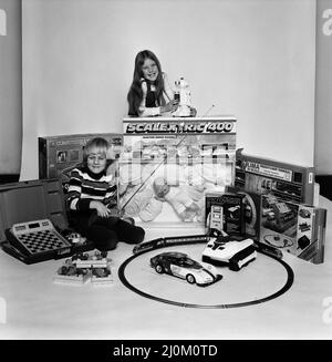 Un ragazzo e una ragazza con una selezione di giocattoli per bambini per Natale. Dicembre 1980. Foto Stock