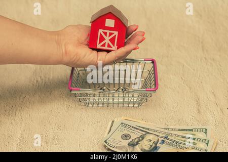 Casa rossa con una pila di fatture del dollaro. Il concetto di acquisto di una casa. Foto Stock