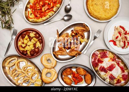 Tapas del ristorante spagnolo allestite con uova strapazzate con prosciutto iberico, ali di pollo fritte, polpette con patate, calamari andalusi, frittata di patate e. Foto Stock