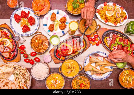 Set di piatti indiani con le mani che pocano il pollo tikka masala, un altro sui samosas ripieni e curry Foto Stock