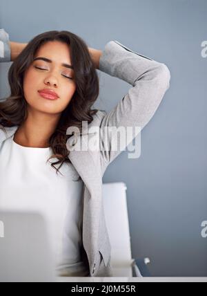 Shes sensazione piuttosto rilassato oggi. Scatto corto di una giovane donna d'affari che guarda rilassato mentre lavora sul suo laptop. Foto Stock