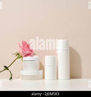 Tubi e vasetti vuoti in plastica bianca per cosmetici. Confezione per crema, gel, siero, pubblicità e promozione del prodotto Foto Stock