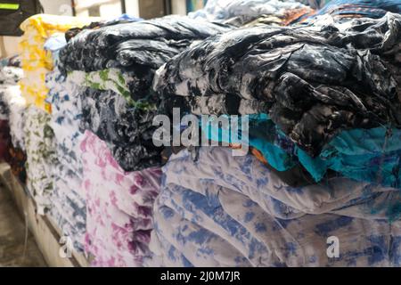 Una pila di asciugamani multicolore su sfondo chiaro, vista laterale. Primo piano di una pila di tappeti colorati in vendita in Indonesia ad un mercato. Foto Stock