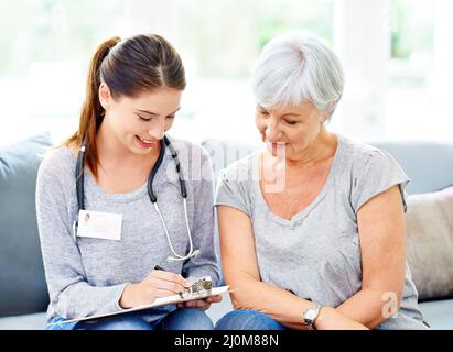 Questi risultati sembrano molto promettenti.... Un medico che spiega i risultati positivi dei test a un paziente anziano sorridente. Foto Stock