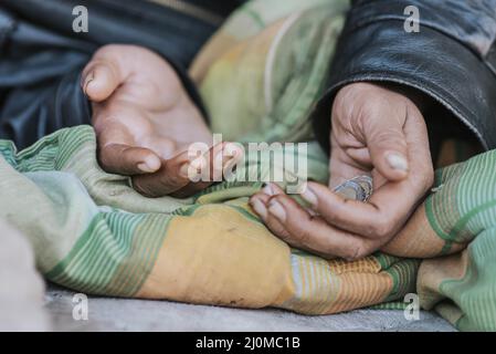 Donna senza tetto che tiene le mani fuori per aiuto Foto Stock