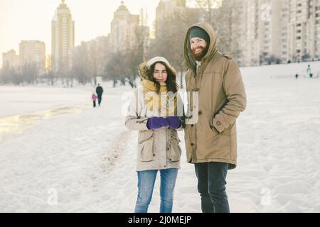 Tema amore e data sulla natura. Un giovane ragazzo e una ragazza della coppia eterosessuale caucasica camminano in inverno lungo un lago ghiacciato in wint Foto Stock