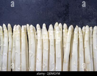 Bianco grezzo Asparagus bordato in una fila come primo piano con spazio di copia Â– isolato su sfondo nero Foto Stock