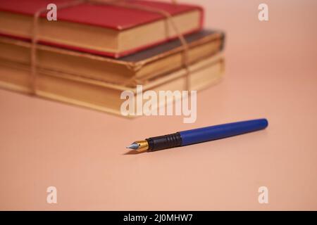 Una pila di vecchi libri in batteria legati con una corda di iuta e una penna stilografica Foto Stock