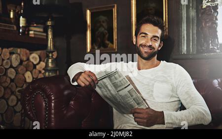 Recuperare gli eventi attuali. Ritratto di un bell'uomo che legge un giornale in un caffè. Foto Stock