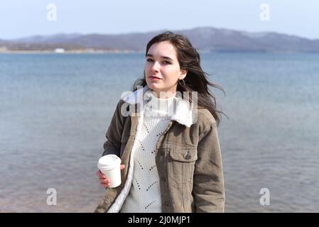 Giovane donna russa che beve caffè contro il mare giapponese in primavera Foto Stock