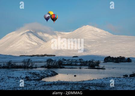 Immagine composita digitale di palloncini ad aria calda che volano sopra la bella immagine di paesaggio in inverno guardando attraverso Lochan Na h-Achlaise verso la catena montuosa Foto Stock