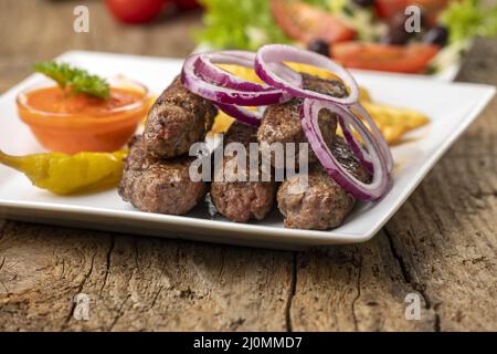 Cevapcici su un piatto su legno Foto Stock