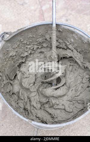 Miscelazione di una soluzione di gesso con un trapano elettrico. Miscelazione dell'adesivo. Ristrutturazione della casa. Foto Stock