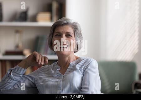 Bella donna anziana rilassante su un comodo divano nel soggiorno Foto Stock