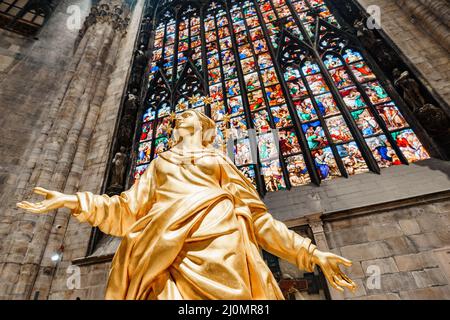 Statua della Madonna in oro sullo sfondo di una vetrata del Duomo. Milano, Italia Foto Stock