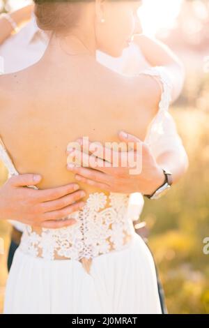 Sibenik, Croazia - 05.06.17: Le mani dello sposo abbracciano il dorso della sposa in un abito in pizzo bianco. Primo piano Foto Stock