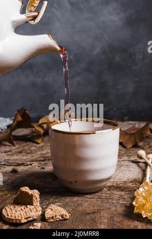 Vista frontale tè che viene versato tazza Foto Stock