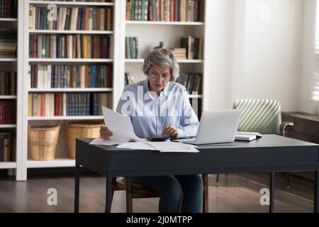 Donna matura che ordina le fatture, occupato nella gestione delle finanze Foto Stock