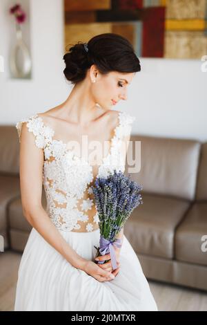 Sibenik, Croazia - 05.06.17: Sposa in un abito in pizzo bianco tiene un bouquet di lavanda legato con un nastro nelle sue mani mentre in piedi Foto Stock