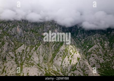 Vista aerea di bellissime montagne rocciose coperte di nuvole nella baia di Cattaro, Montenegro Foto Stock